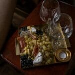 Deska serów z winogronami, wędlinami i kieliszkami wina na drewnianym stole