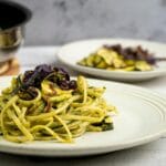 Makaron z pesto i cukinią, udekorowany czerwoną cebulą na talerzu