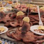 Talerz z ośmiornicą i cytryną na kolorowym straganie w Palermo