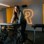 Uśmiechnięta kobieta ćwiczy na rowerze stacjonarnym na siłowni