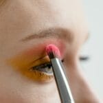 Kobieta nakłada kolorowy cień na powiekę pędzelkiem