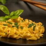 Kremowe cacio e pepe na czarnym talerzu z bazylią i szczypiorkiem