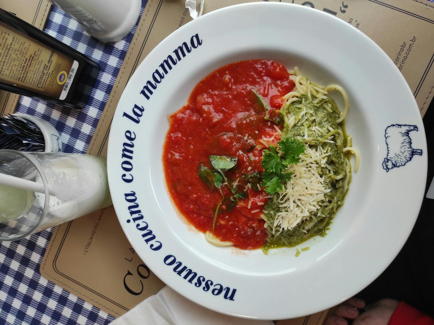 Spaghetti z sosem pomidorowym i zielonym pesto na białym talerzu Spaghetti z sosem pomidorowym i zielonym pesto na białym talerzu