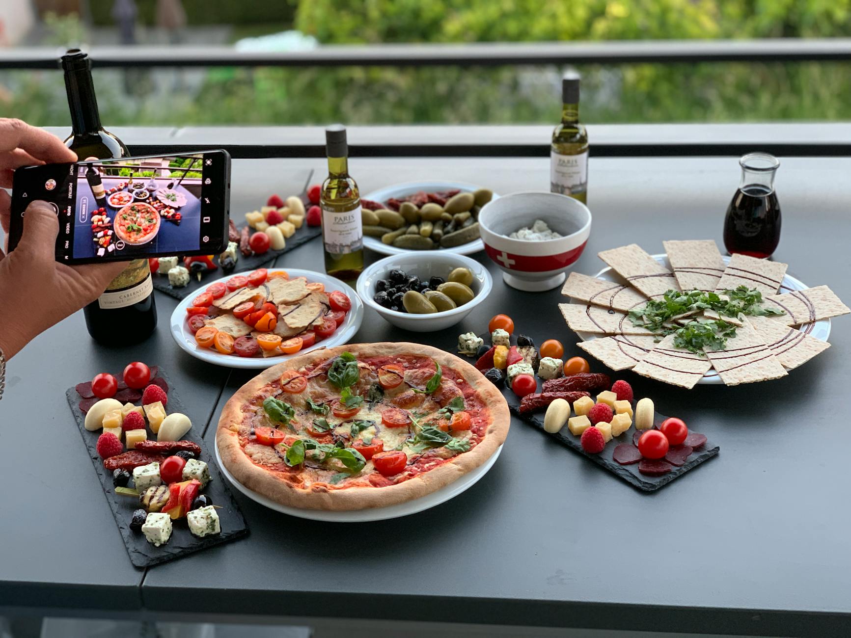 Włoska pizza i przystawki fotografowane smartfonem na tarasie