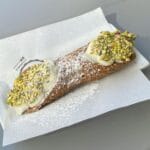 Cannolo sycylijskie z posypką z pistacji na białej serwetce