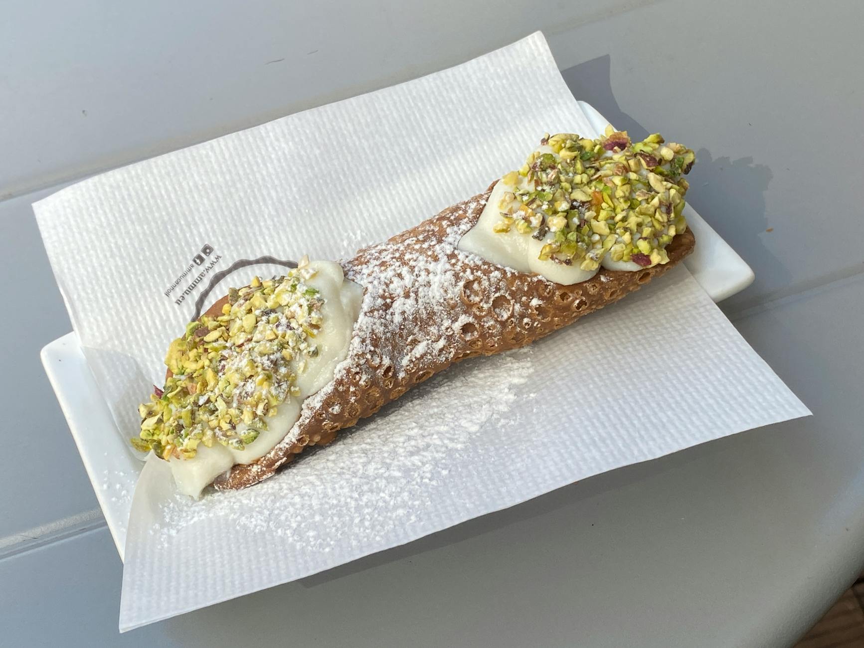 Cannolo sycylijskie z posypką z pistacji na białej serwetce