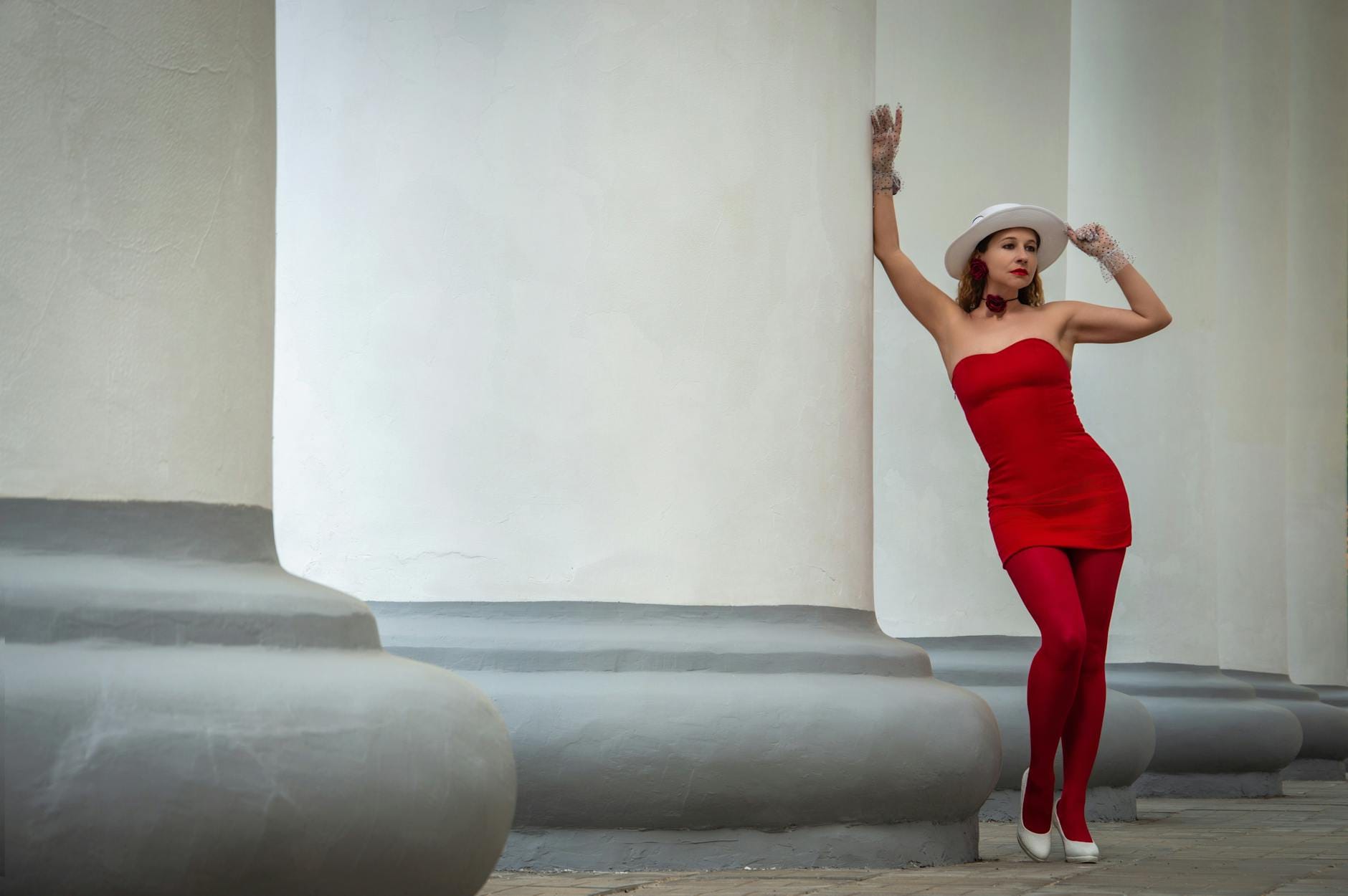 Kobieta w czerwonej stylizacji przy klasycznych kolumnach