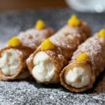 Zbliżenie na sycylijskie cannoli z kremem i cukrem pudrem na talerzu