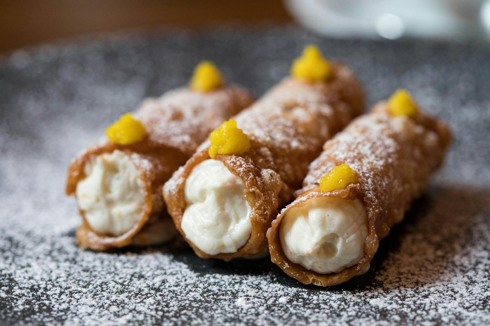 Cannoli siciliani: chrupiące rurki i krem jak z Palermo Zbliżenie na sycylijskie cannoli z kremem i cukrem pudrem na talerzu