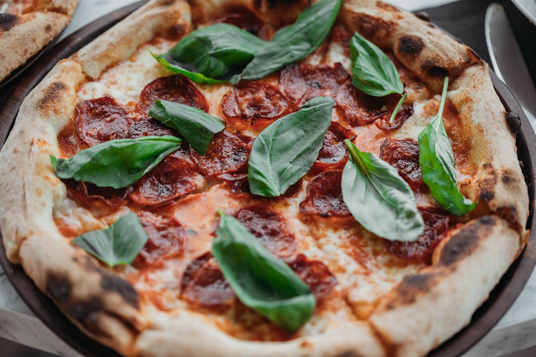 Pizza pepperoni z listkami świeżej bazylii