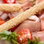 Grissini domowe: cienkie paluszki idealne do prosciutto Włoski półmisek z grissini, prosciutto i pomidorkami koktajlowymi