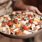 Sałatka panzanella z pomidorami i ziołami na brązowym półmisku