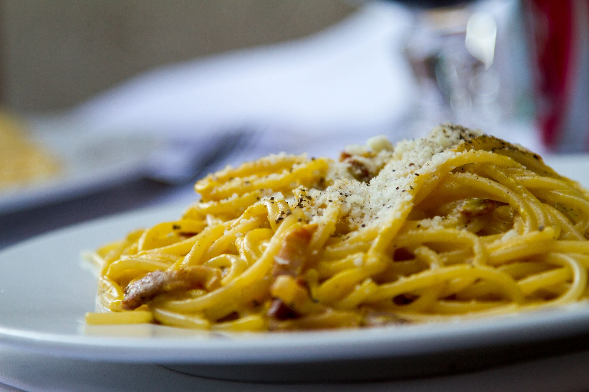 Spaghetti carbonara z tartym parmezanem na talerzu