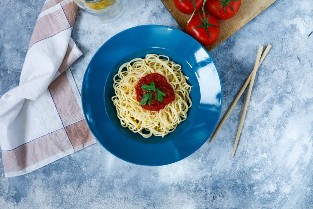 Spaghetti w sosie pomidorowym z pietruszką na niebieskim talerzu
